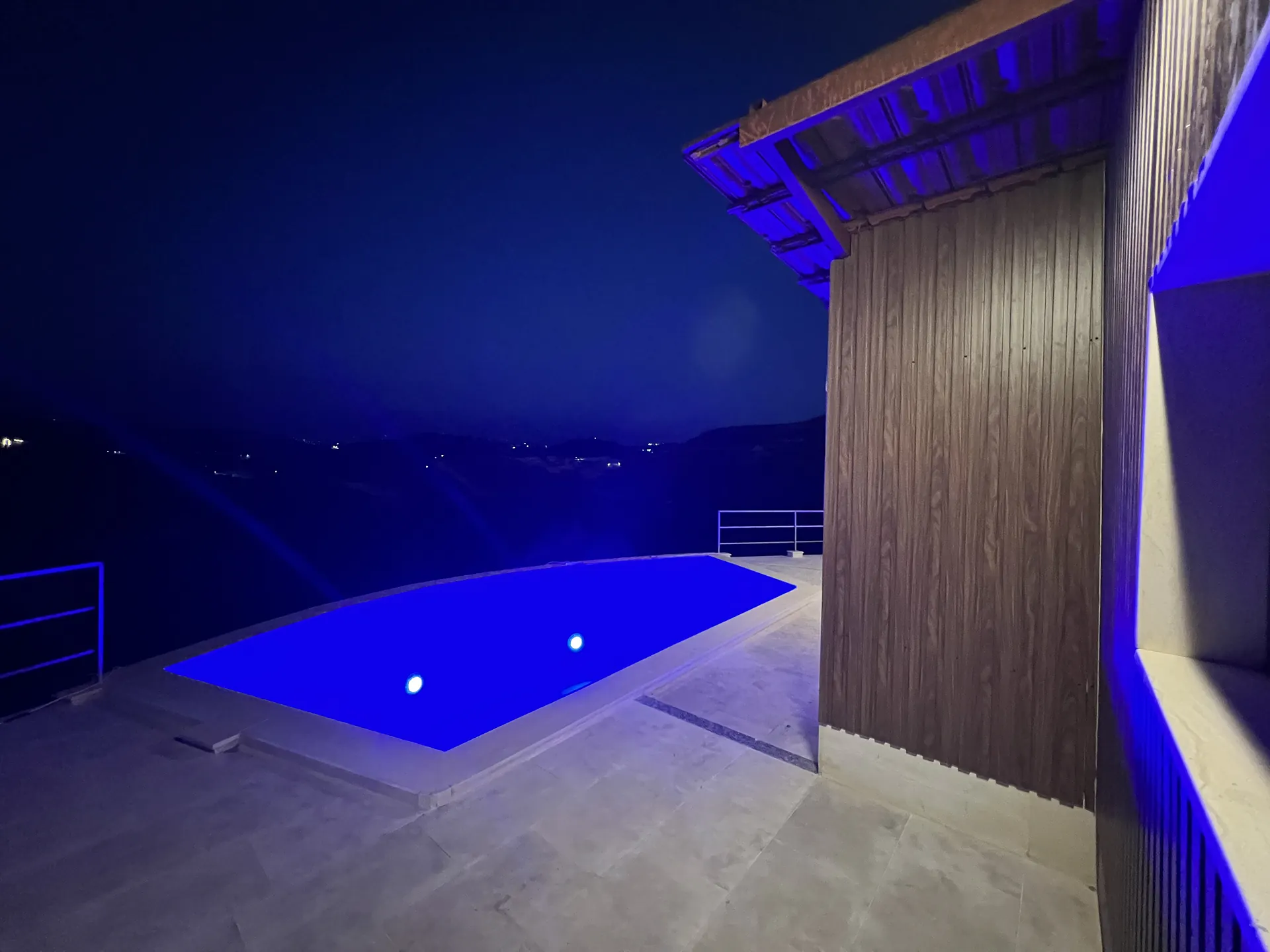 The pool lit blue after dark, with the valley lights below